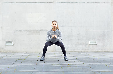 Image showing woman doing squats and exercising outdoors