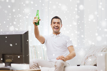 Image showing smiling man watching tv and drinking beer at home