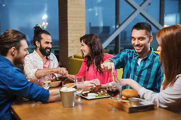 Image showing friends eating and tasting food at restaurant