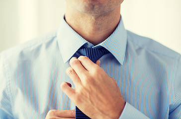 Image showing close up of man in shirt adjusting tie on neck