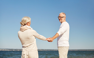 Image showing happy senior couple holding hands summer beach