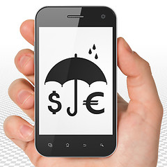 Image showing Security concept: Hand Holding Smartphone with Money And Umbrella on display