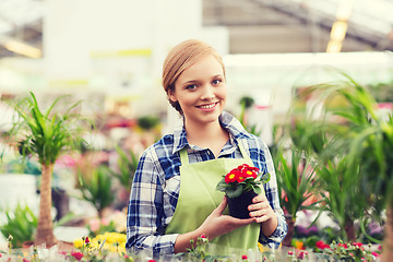 Image showing happy woman holding flowers in greenhouse