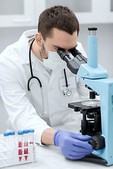 Image showing young scientist looking to microscope in lab