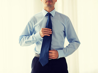 Image showing close up of man in shirt adjusting tie on neck