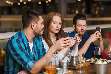 Image showing friends with smartphones dining at restaurant