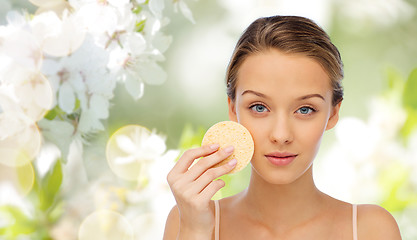 Image showing young woman cleaning face with exfoliating sponge