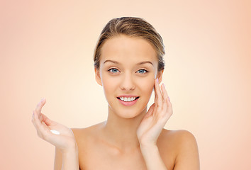 Image showing happy young woman applying cream to her face