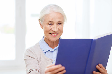 Image showing happy smiling senior woman reading book at home