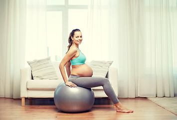 Image showing happy pregnant woman exercising on fitball at home