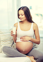 Image showing happy pregnant woman drinking milk at home