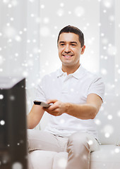 Image showing smiling man with remote control watching tv