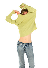 Image showing Woman in jeans takes off a green sweater