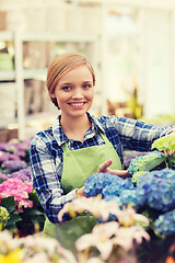 Image showing happy woman taking care of flowers in greenhouse