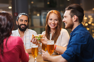 Image showing friends eating pizza with beer at restaurant