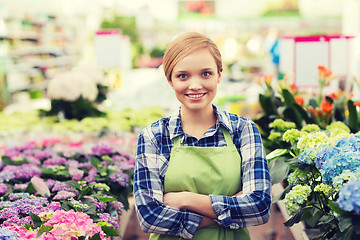 Image showing happy woman with flowers in greenhouse