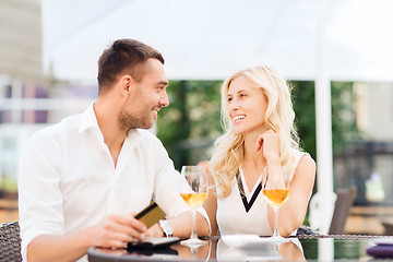 Image showing happy couple with bank card and bill at restaurant