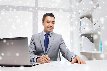 Image showing smiling businessman with laptop and papers