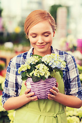 Image showing happy woman smelling flowers in greenhouse