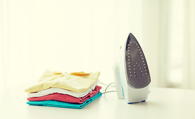 Image showing close up of iron and clothes on table at home