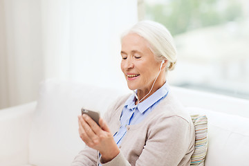 Image showing senior woman with smartphone and earphones at home