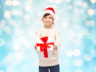 Image showing smiling happy boy in santa hat with gift box