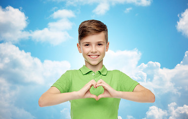 Image showing happy boy showing heart hand sign over blue sky