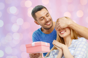 Image showing smiling man surprises his girlfriend with present