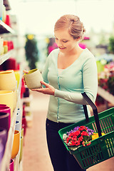 Image showing woman with shopping basket choosing flowerpot