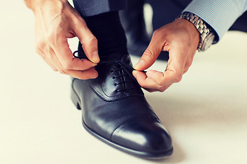 Image showing close up of man leg and hands tying shoe laces