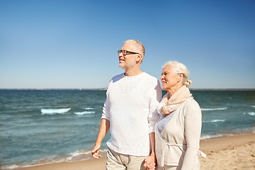 Image showing happy senior couple walking along summer beach