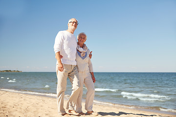 Image showing happy senior couple walking along summer beach