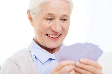 Image showing happy senior woman playing cards at home