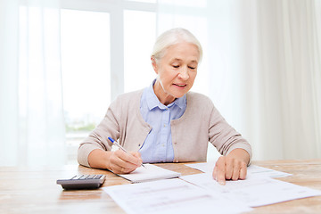 Image showing senior woman with papers and calculator at home