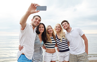 Image showing happy friends on beach and taking selfie