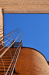 Image showing Industrial ladder, blue sky and brick walls of the building