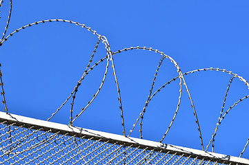 Image showing Fence with a barbed wire against the blue sky. 