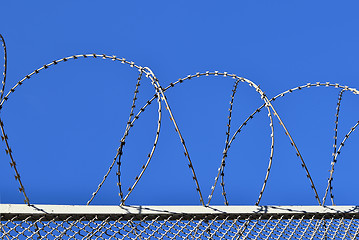 Image showing Fence with a barbed wire against the blue sky. 