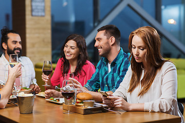 Image showing woman with smartphone and friends at restaurant