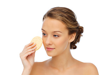 Image showing young woman cleaning face with exfoliating sponge