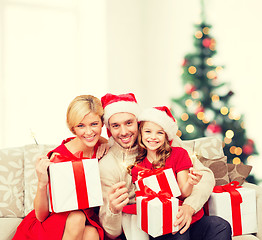 Image showing smiling family holding gift boxes and sparkles