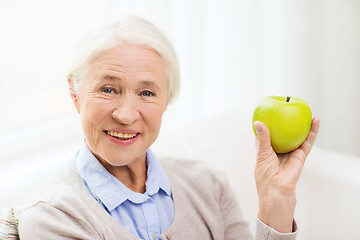 Image showing happy senior woman with green apple at home