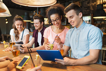 Image showing happy friends with tablet pc and drinks at bar