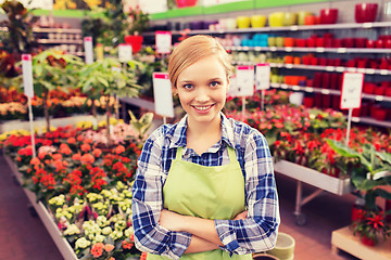 Image showing happy woman with flowers in greenhouse