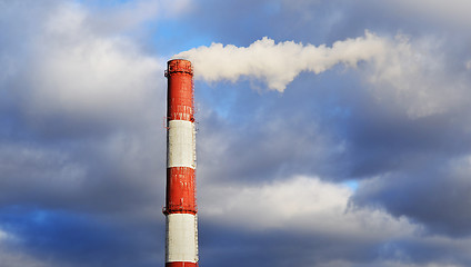 Image showing Pipe industrial chimney with smoke against the sky and clouds