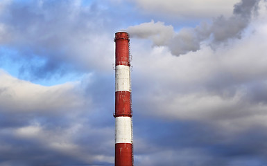 Image showing Pipe industrial chimney with smoke against the sky and clouds