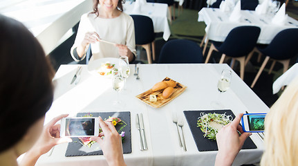 Image showing close up of women picturing food by smartphones