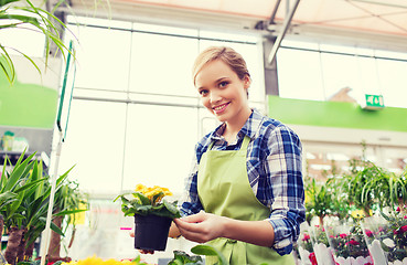 Image showing happy woman holding flowers in greenhouse