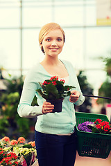 Image showing happy woman with shopping basket choosing flowers