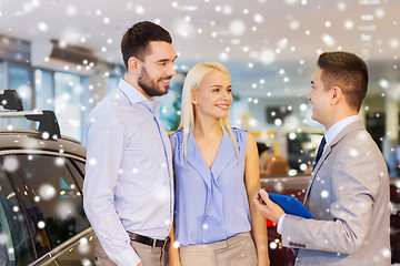 Image showing happy couple with car dealer in auto show or salon